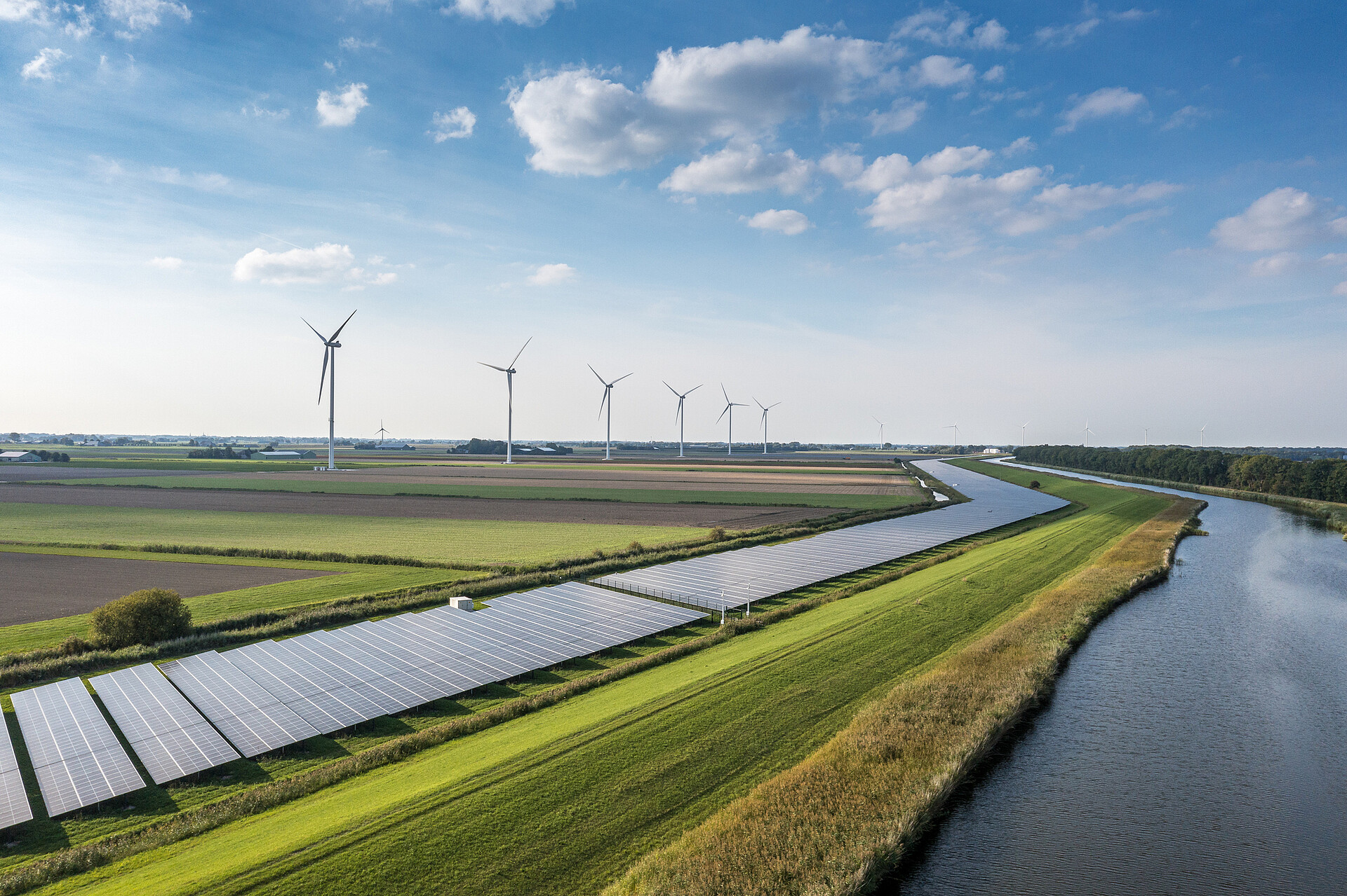 Feld mit Solaranlage und Windrädern