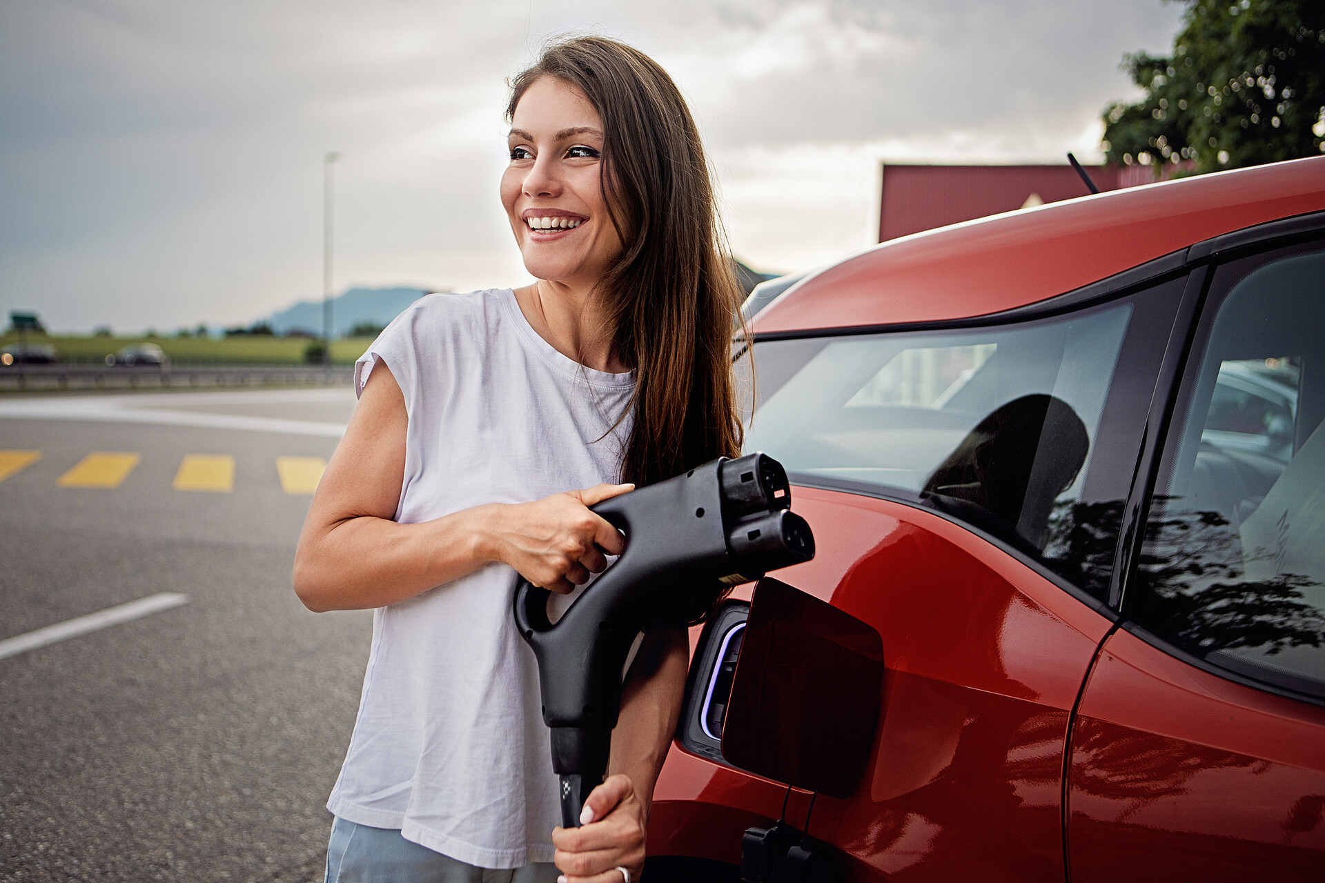 Frau lädt ein rotes Elektroauto