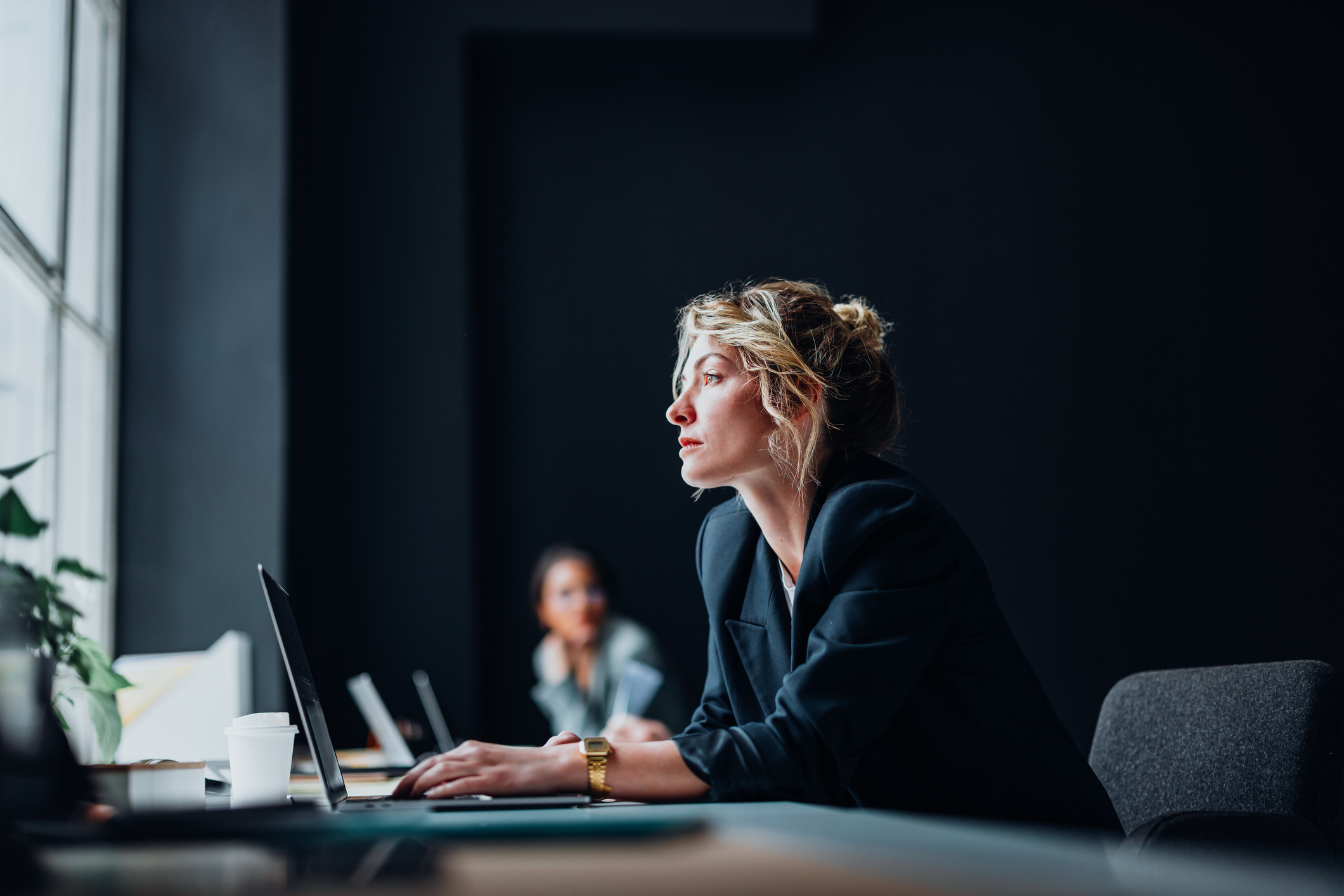 Business-Frau mit Notebook blickt in die Ferne